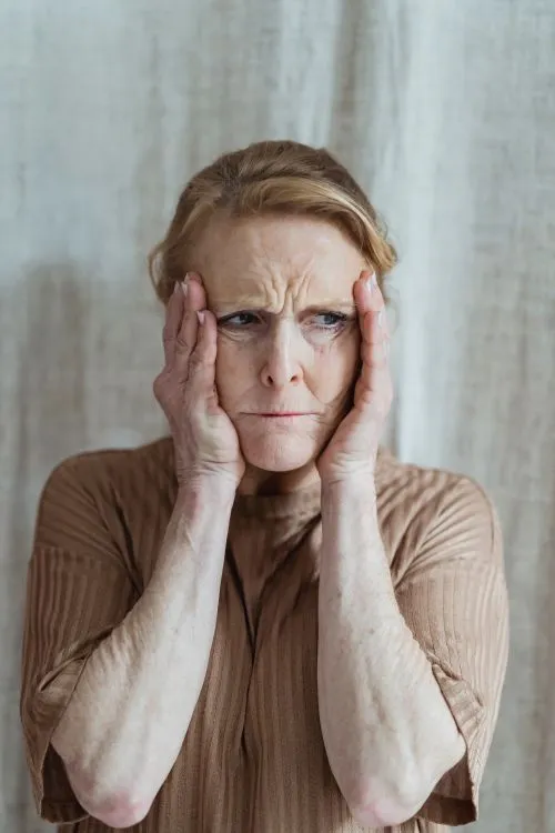 A tired grandparent at a kitchen table with scattered items