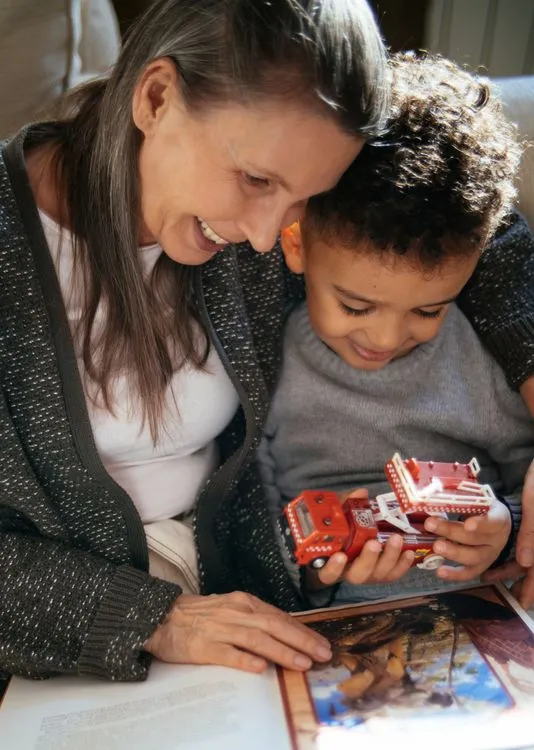 A happy grandparent reading to a grandchild in a cozy room