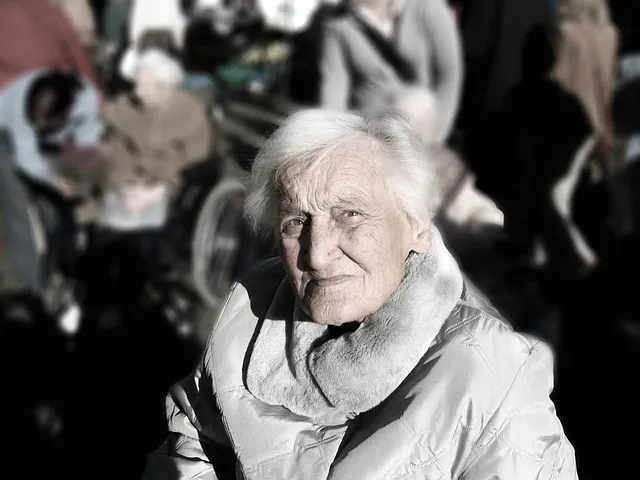 An aging parent sitting alone in a bright sunlit room looking out the window