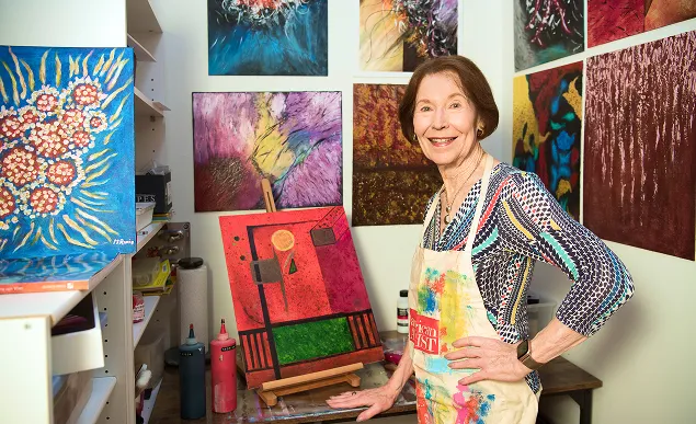 A Judson Manor resident proudly displaying her artwork in her painting studio