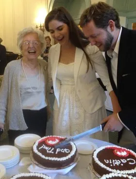Former artist-in-residence couple cutting wedding cake at Judson Manor with resident beaming beside them
